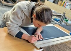 Johanna Thielges arbeitet konzentriert an einem Möbelstück. Das ausgewählte Furnierblatt ist bereits für die Weiterverarbeitung vorbereitet. Foto: Kevin Thielges