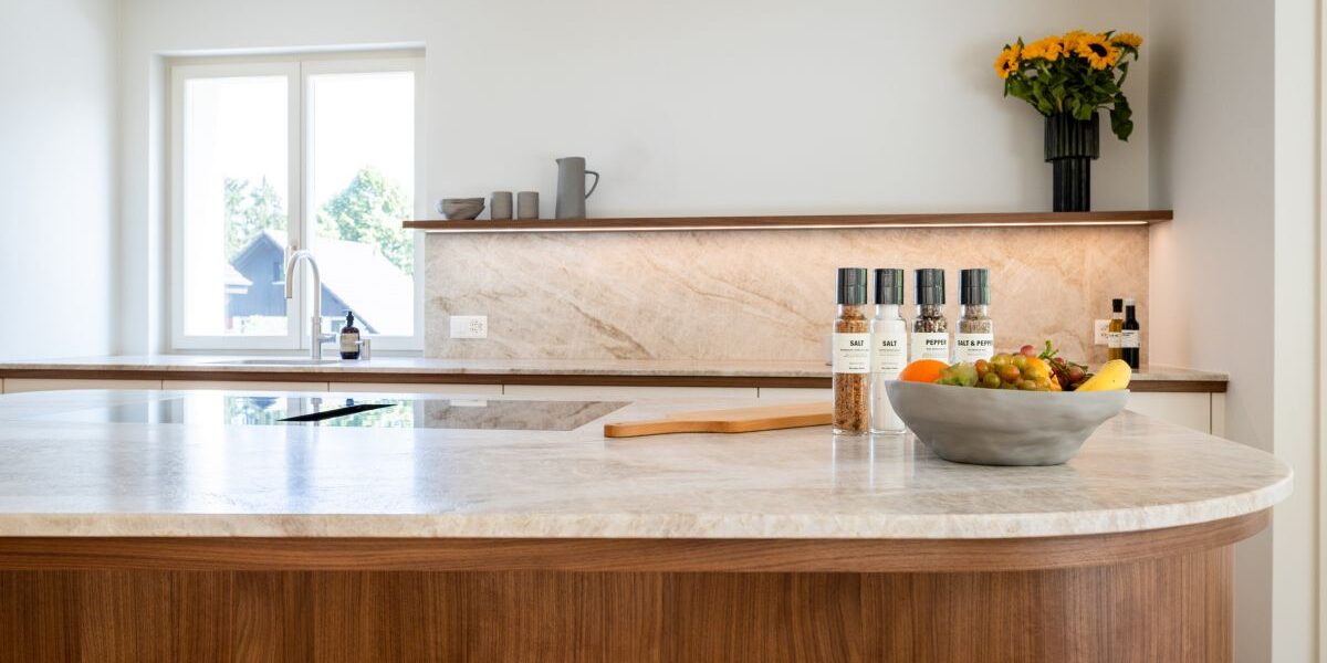 Die Maserung und die harmonische Farbgebung des Nussbaum‑Furniers bilden einen eleganten Kontrast zu den hellen Fronten der Küche. Fotos: © Davidküchen Basel